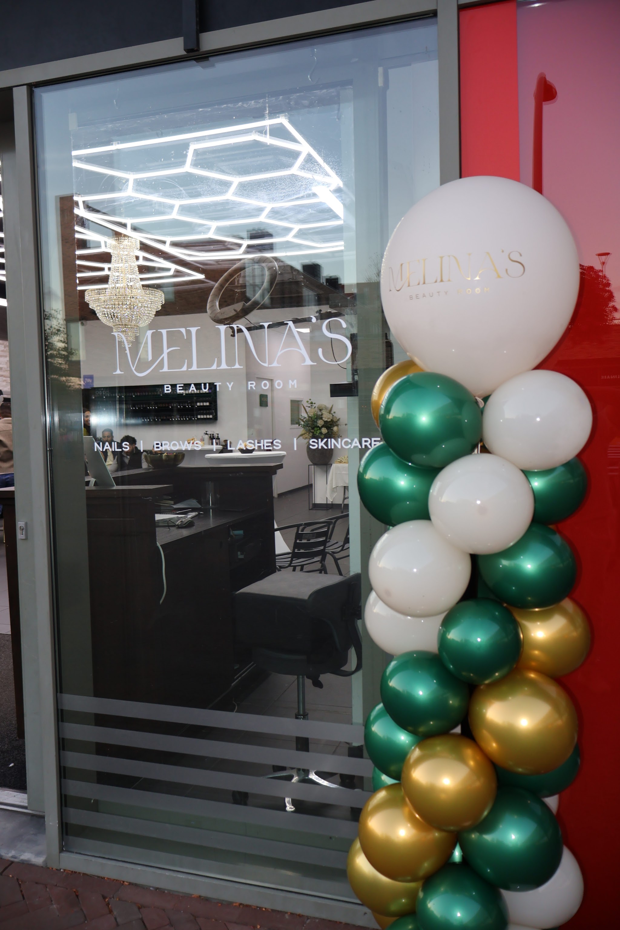 De glazen pui van Melina’s Beauty Room met het logo en ballonnen bij de opening